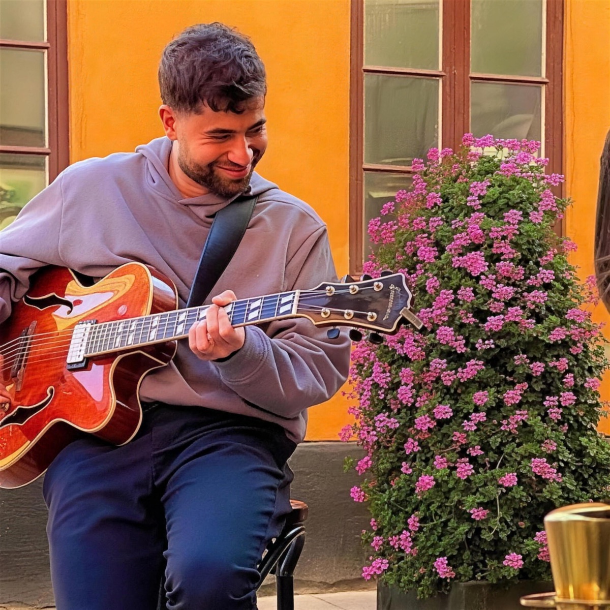 Armin Mir smiling with his archtop guitar